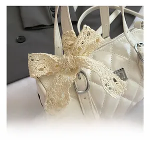 Detail showing cream quilted handbag with lace bow and silver metal clasp closure