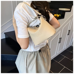 Detail view of the beige leather shoulder bag showing geometric design and silver hardware
