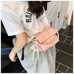 Sac à main tissé rose avec nœud en dentelle perle porté par un mannequin en salle