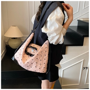 Detail of pink bow-patterned tote bag with black leather bottom and heart pendant