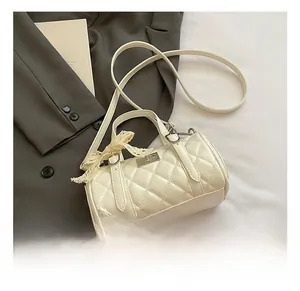 Detail of cream quilted cylinder bag with lace bow decoration on a stylish backdrop