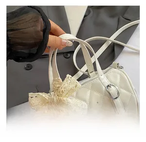 Detail of white cylinder bag featuring quilted texture and delicate lace bow decoration