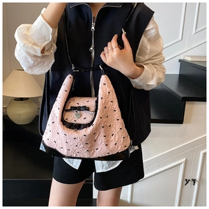 Detail of light pink tote bag with black bow patterns and heart-shaped metal pendant charm