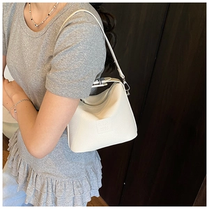 Close-up of off-white lychee grain leather crossbody bag with silver metal zipper details
