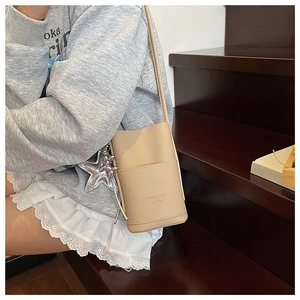 Close-up of beige lychee grain leather phone bag with silver star and dog charms