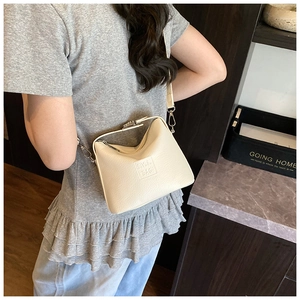 Close-up of cream white lychee leather texture and embossed logo on minimalist shoulder bag