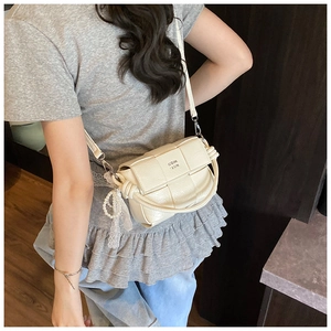 Détail du sac bandoulière tissé crème avec breloque en dentelle et perles