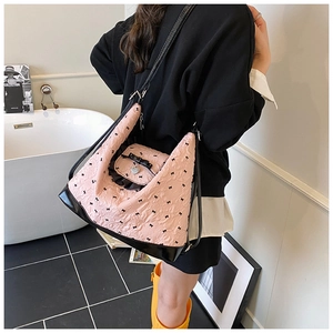 Pink and black tote bag featuring bow patterns and heart charms in a stylish lifestyle setting