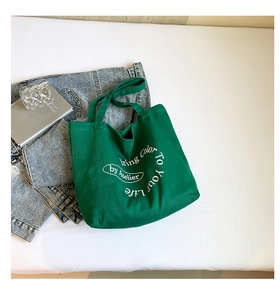 Detail of green canvas tote bag featuring white artistic lettering and thick fabric texture