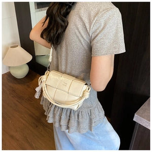 Détail d'un sac demi-lune tissé crème avec breloque en dentelle et perles de luxe