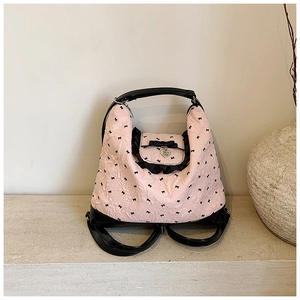 Detailed view of the pink tote bag featuring black bow patterns and textured floral lace edges