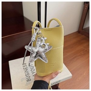Detail of yellow lychee texture leather mini crossbody bag with star and balloon dog charms