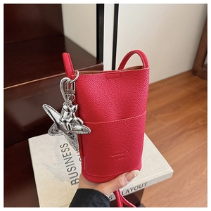 Detail of red lychee grain leather mini crossbody bag with a cute balloon dog charm