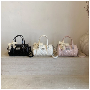 Three quilted pillow bags in black, white, and pink with lace bows on stone stairs
