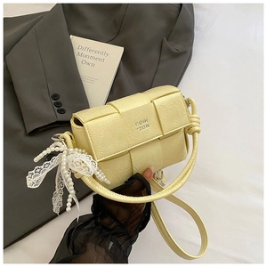 Détail du sac tressé jaune avec nœud décoratif en perles et poignée nouée