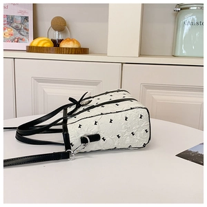Détail du sac cabas blanc avec broderie de lettres et petit nœud noir décoratif