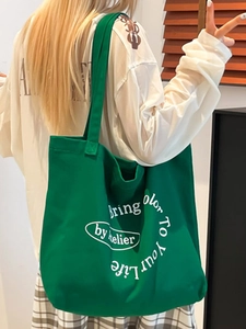 Vibrant green canvas tote bag with artistic letter print and wide shoulder strap