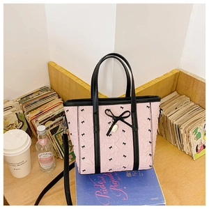 Détail du sac seau rose avec motifs nœuds noirs et breloque en cœur doré élégant