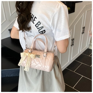 Detail of pink quilted cylindrical bag with lace bow charm and silver metallic clasp