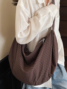 Brown checkered large capacity tote bag worn by a model in a casual fashion setting