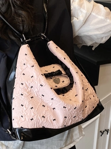 Pink bubble fabric backpack with black bows and heart pendant shown on model