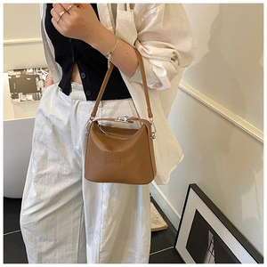 Detail of a brown leather bucket bag with silver hardware and S.Y.&. BAG embossed logo