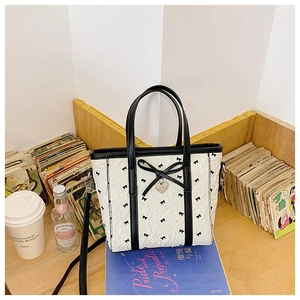 Détail du sac à main blanc texturé à bulles avec imprimé nœud noir et pendentif cœur