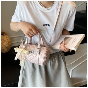 Pink quilted barrel bag with lace bow and metal lock shown in a crossbody style