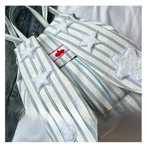 Detail showing blue striped backpack with white plush star patches and colorful bead drawstrings