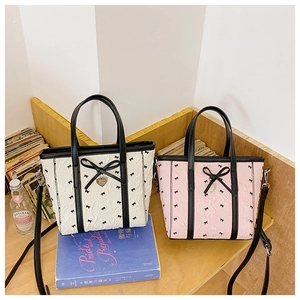 Détail de mini sacs cabas avec texture plissée, nœud noir et pendentif cœur sur étagère