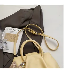 Detail of beige cloud bag with pleated leather texture and a checkered bow charm