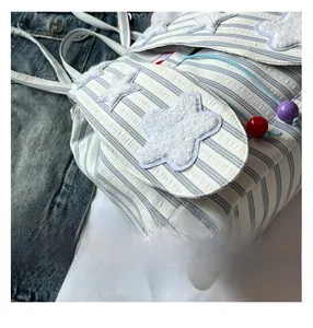 Detail of blue and white striped canvas backpack featuring plush stars and colorful beads
