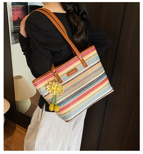 Detail of colorful rainbow woven beach tote with brown leather handles and crochet flower charm