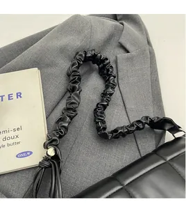 Détail du sac bandoulière en cuir noir matelassé avec une sangle froncée élégante