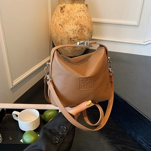 Detail of brown litchi grain leather shoulder bag with embossed S.Y.& BAG logo and silver zip