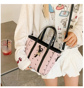 Détail du sac cabas rose imprimé nœuds avec bordure noire et pendentif cœur doré