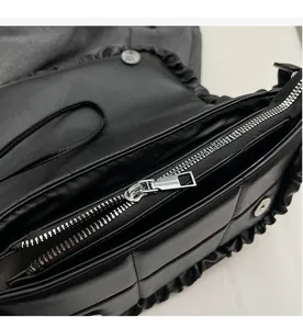 Détail de la fermeture éclair argentée et de l'intérieur d'un sac à bandoulière plissé