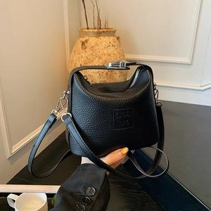 Detail of black litchi grain leather bag with silver zippers and S.V.G brand logo