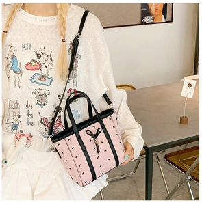 Détail du sac cabas rose imprimé nœuds avec poignées noires dans un cadre de vie