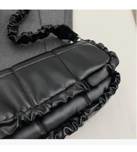 Détail du sac noir matelassé avec bords plissés et bandoulière à volants élégante