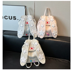 Close-up of cute rabbit ears and apple embroidery on striped seersucker backpacks