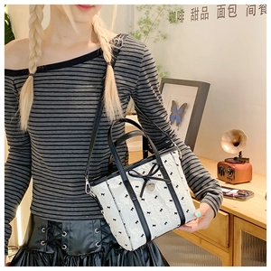 Vue détaillée du petit sac seau blanc avec imprimé nœuds noirs et breloque cœur en métal