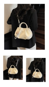 Detail view of cream pleated cloud bag with heart pearl charm and detachable shoulder strap