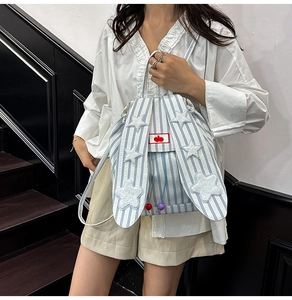 Blue striped canvas backpack with cute bunny ears and plush star patches on model