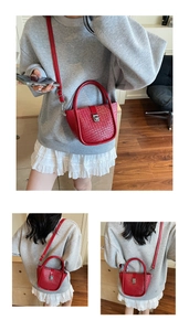 Détail du sac seau rouge tressé avec fermoir en métal argenté et bandoulière