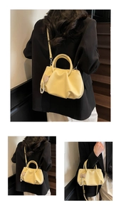 Detail of yellow pleated cloud bag with pearl heart charm and shoulder strap details
