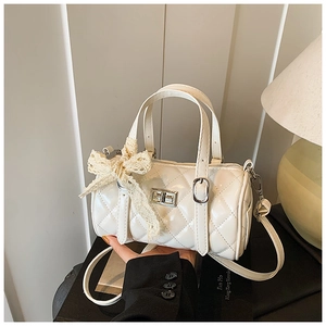Detail of quilted barrel bag featuring lace bow and silver metal twist lock closure