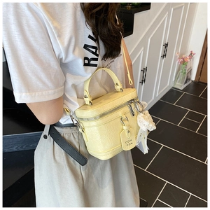 Detailed view of yellow vintage box bag with textured leather and pearl lace charm