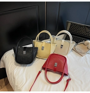 Détail de sacs seaux en cuir tressé noir, jaune, blanc et rouge avec boucles métalliques