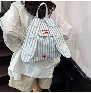 Close-up of cute bunny ear canvas backpack with blue stripes and plush star patches